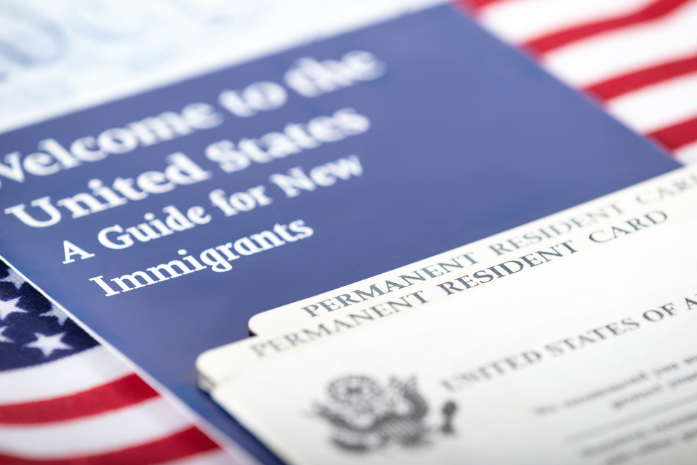 Cover of pamphlet--Welcome to the United States: A Guide for New Immigrants. On top of that, the top edge of a Permanent Resident Card.