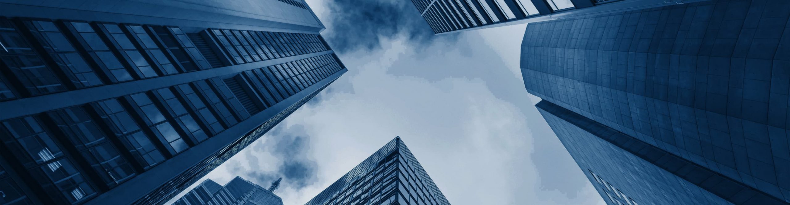 Looking up from the ground toward the sky and the glass exteriors of skyscrapers.