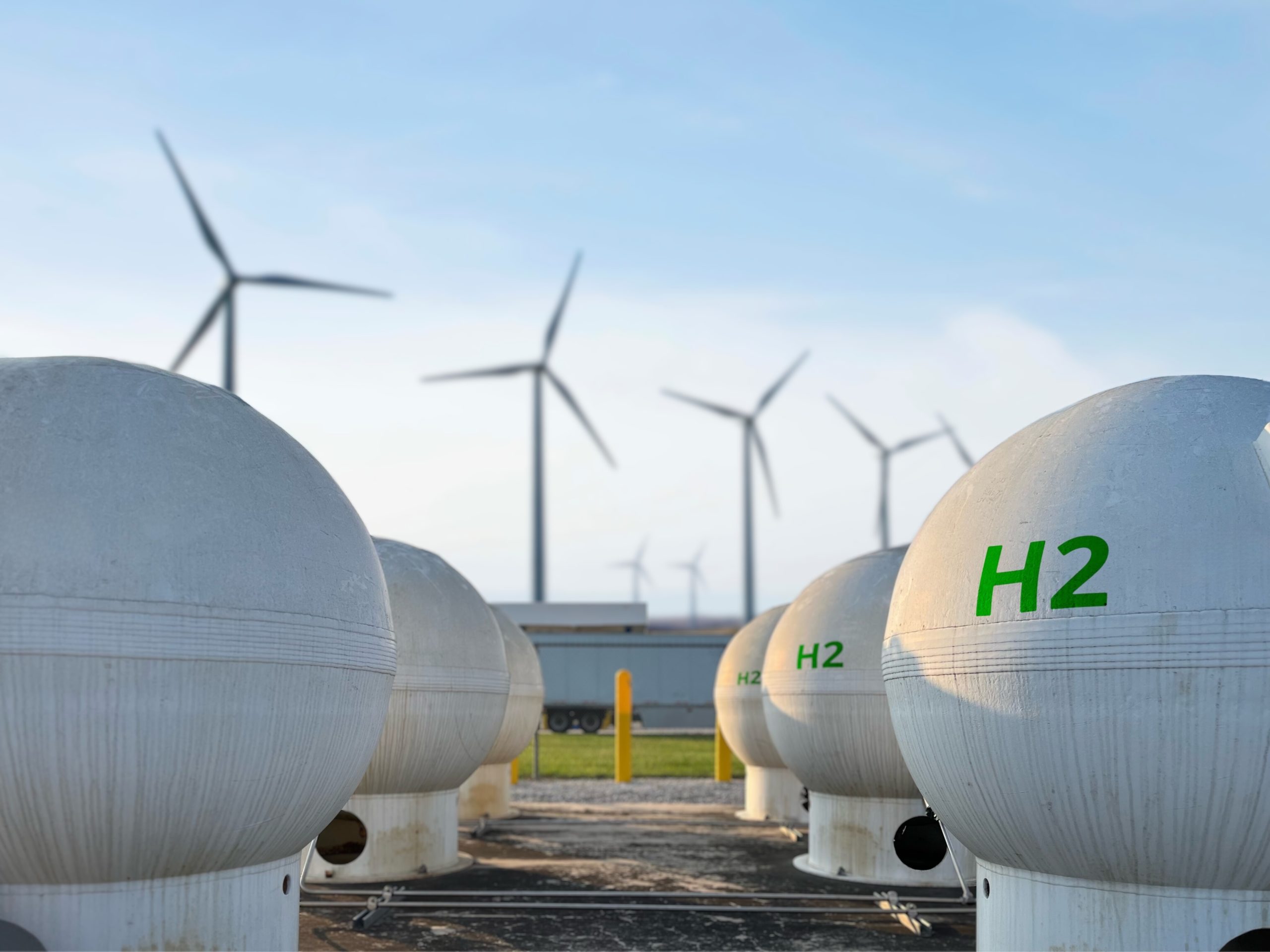 Rows of H2 tanks, with wind turbines in the background.