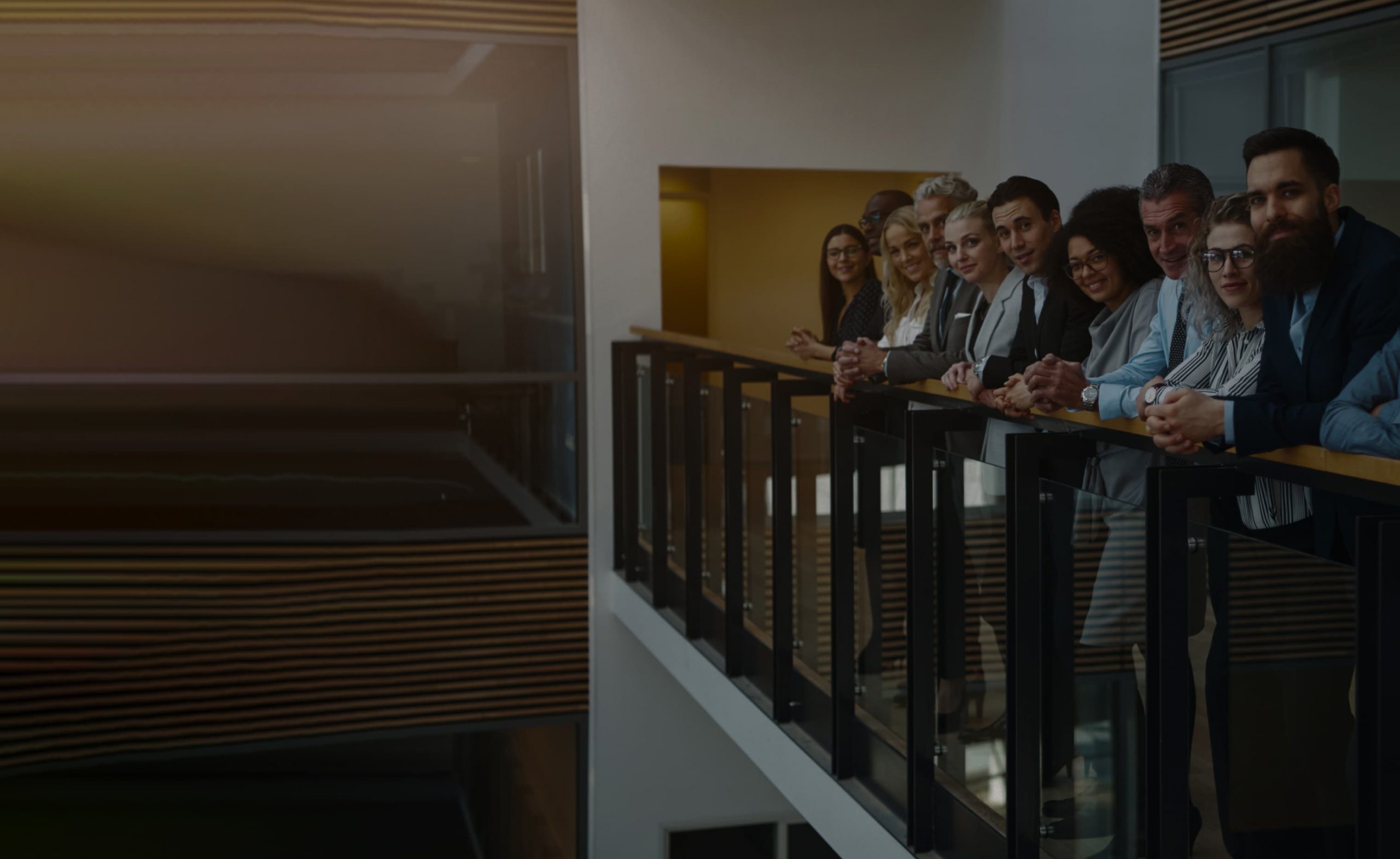 Staff leaning on a rail looking at the camera.