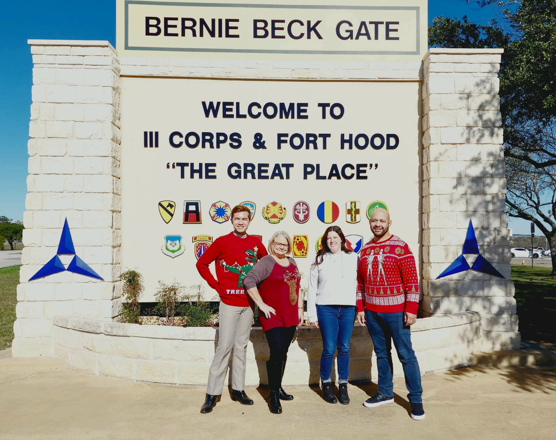 FedWriters employees in Christmas attire posing in front of the Bernie Beck Gate--Welcome to 3rd Corps and Fort Hood, 