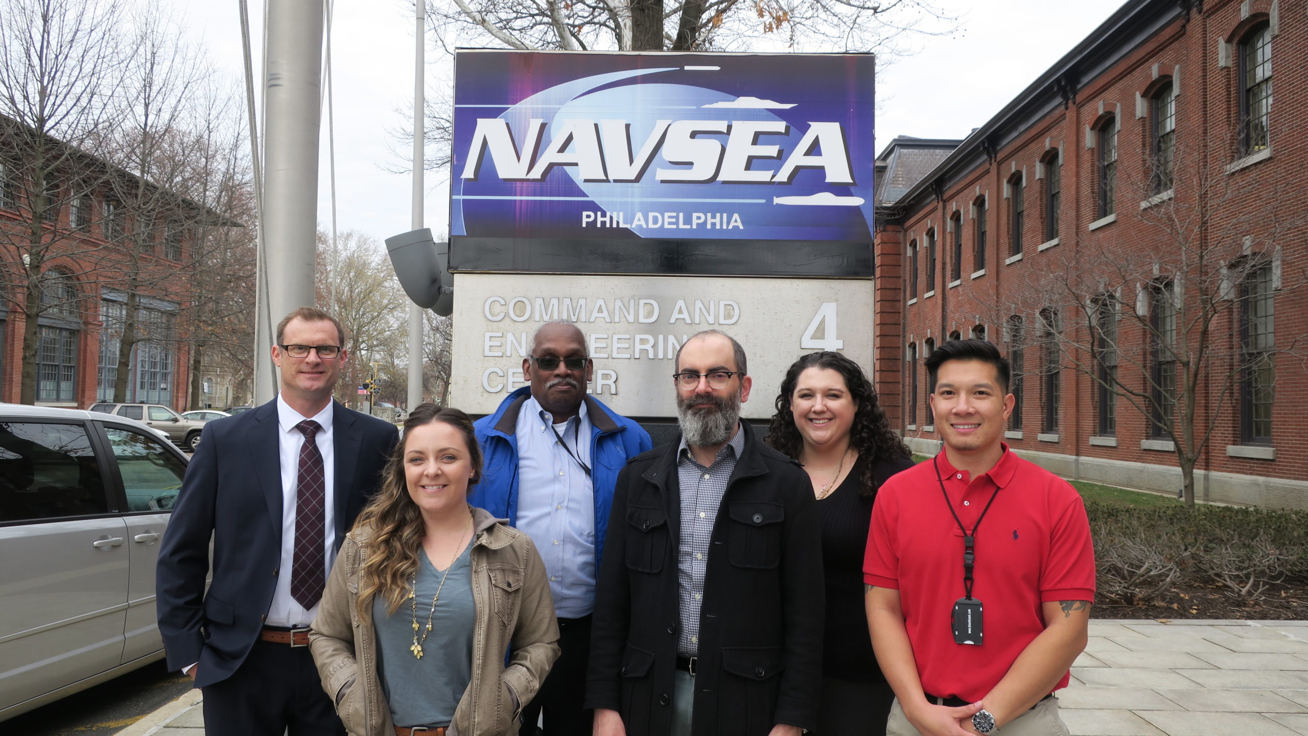 Eric Stone and FedWriters employees standing in front of a sign for the Naval Sea Systems Command in Philadelphia.
