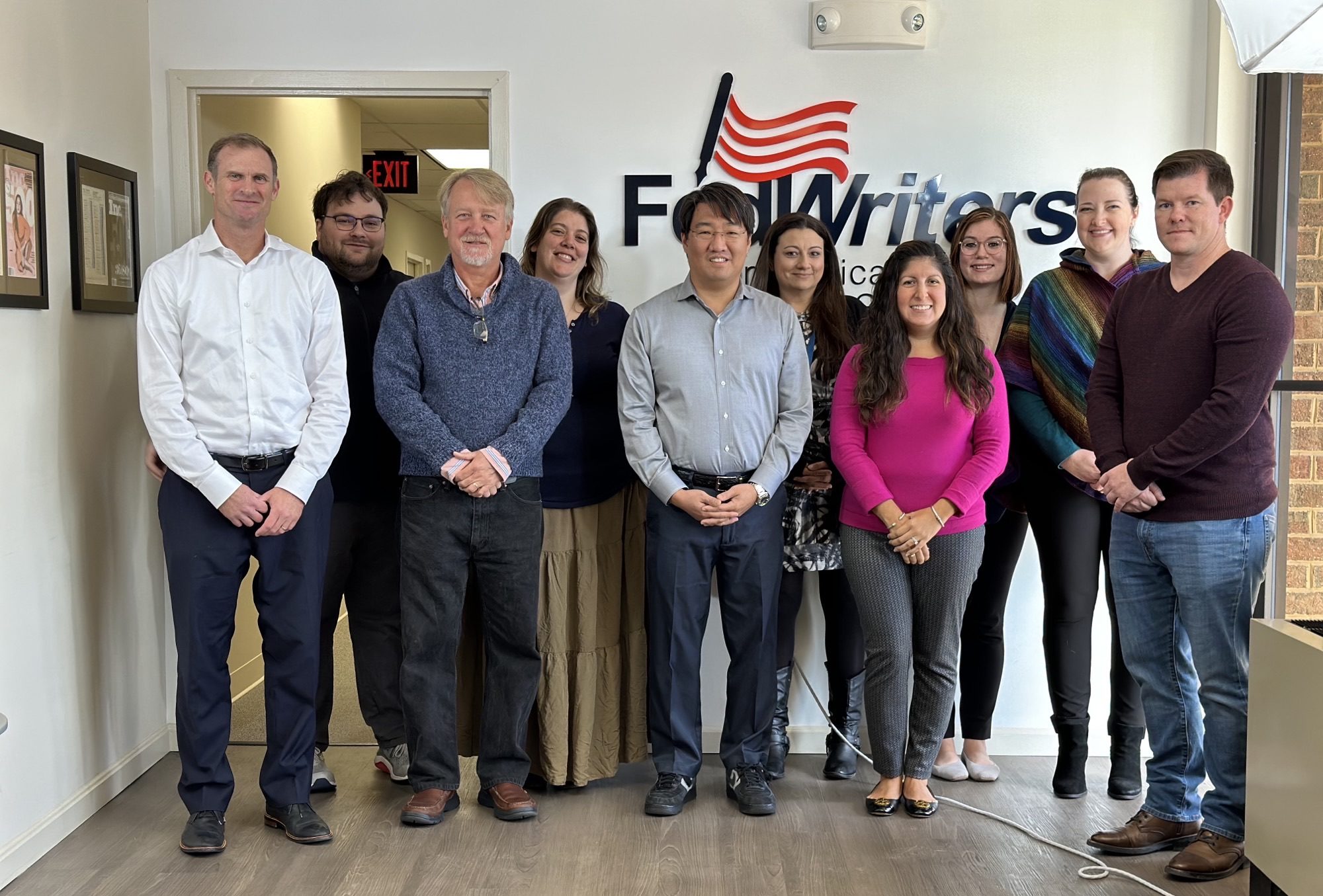 Eric Stone, Marc Fain, Mitchell Cho, Susan Parr, Abigail Casas, and Anthony Stong and FedWriters employees in the headquarters lobby.