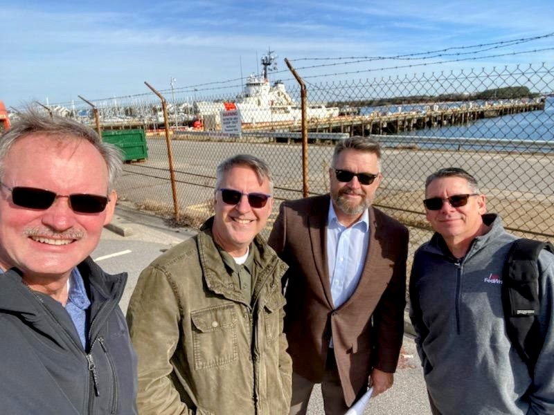 FedWriters employees pose together, with a US Coast Guard cutter docked behind them.