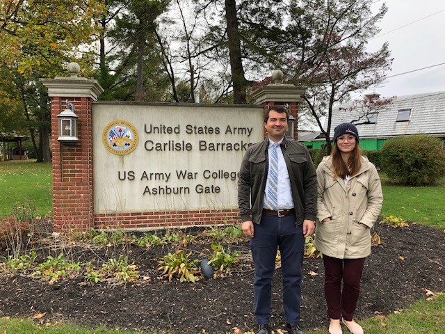 Abigail and Frank stand in front of a brick and concrete sign, which reads 