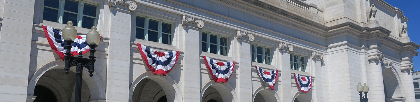 Facade of Washington Union Station, with red, white, and blue sashes draped beneath the windows.