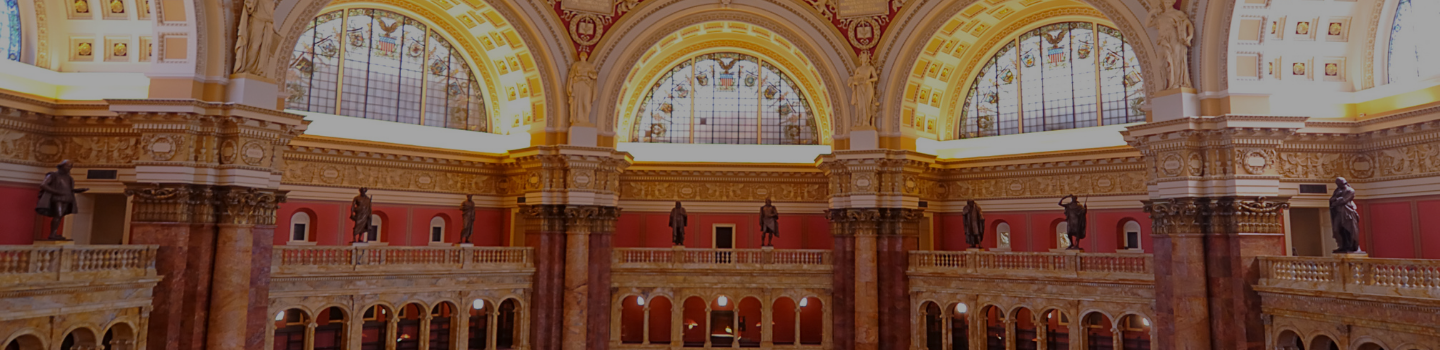 Image of the rotunda of the Library of Congress, called the Reading Room, with large columns, statues, and ornamented arched windows.