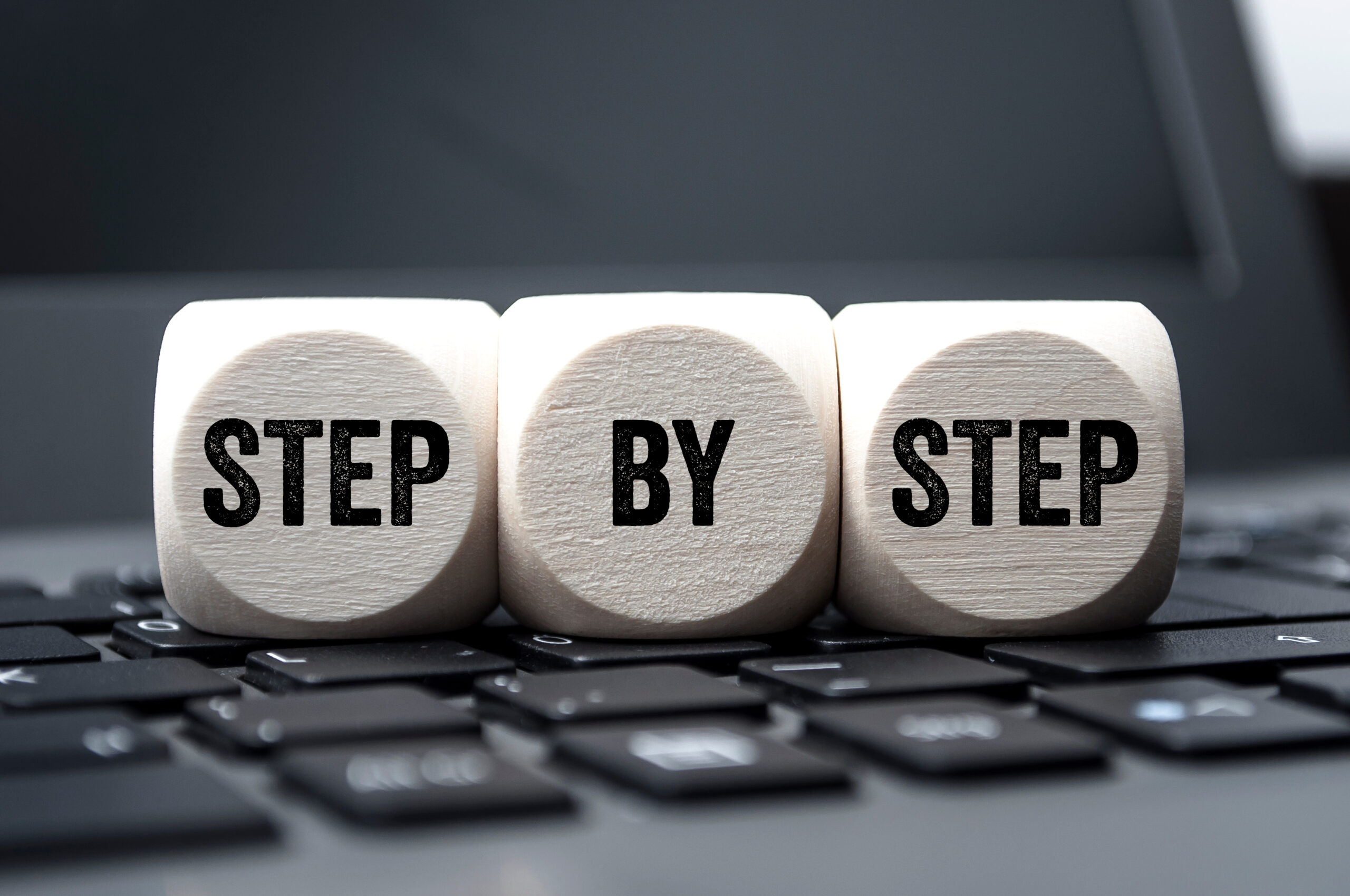 Wooden blocks on a keyboard spelling 'STEP BY STEP', symbolizing a guide to 508 compliance.